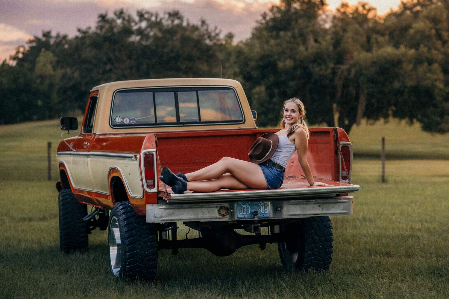 Vintage pickup trucks lined up in an open field at golden hour.