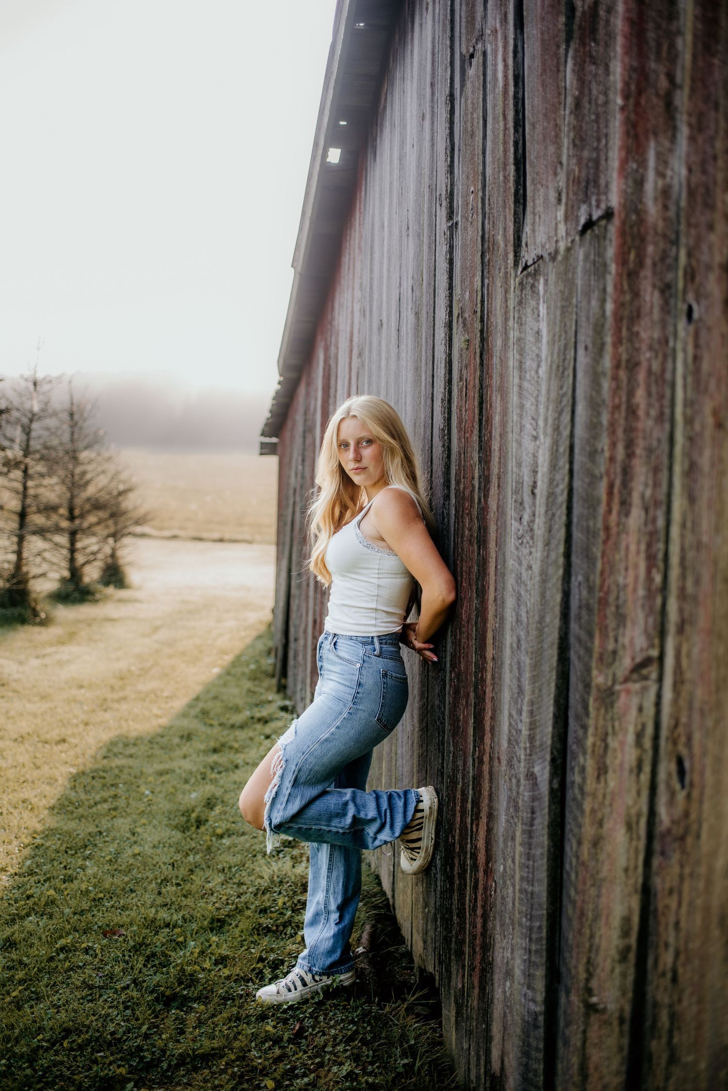 A casual portrait against a rustic barn wall in natural lighting.