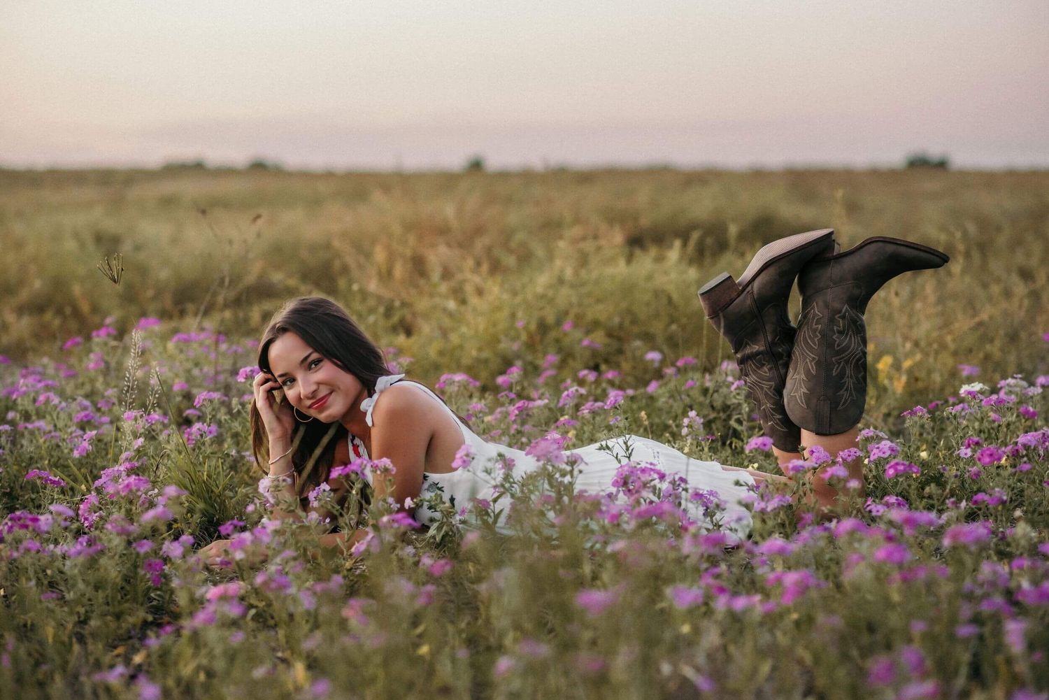 Field of purple wildflowers stretching across rolling countryside at dusk.