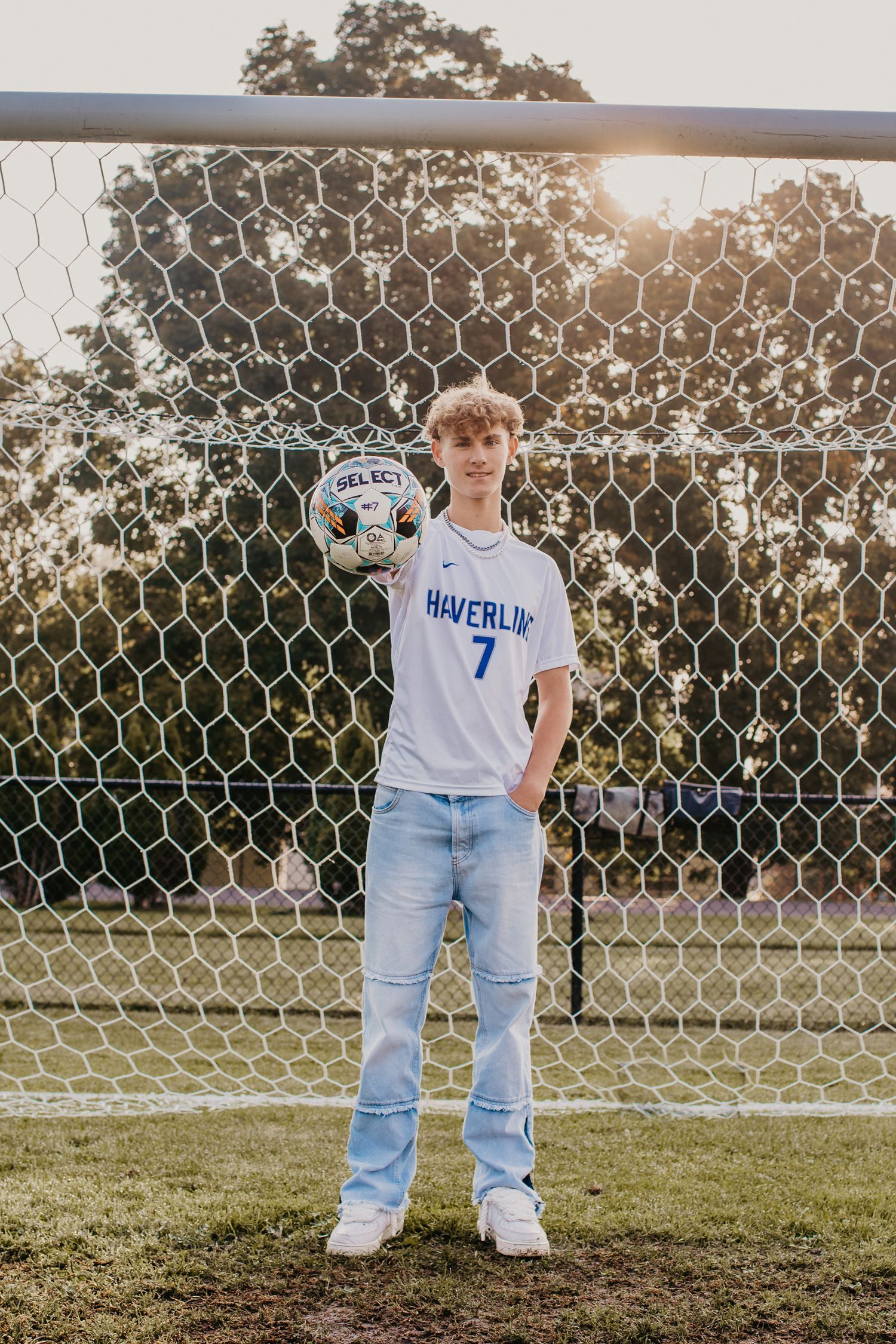 Soccer goal net on grassy field at sunset with casual sportswear.