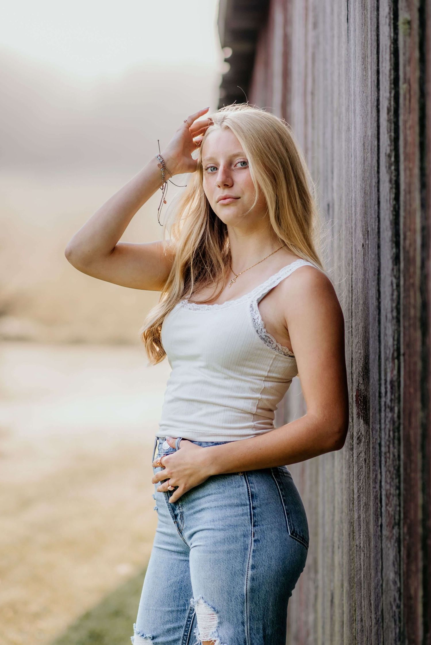 Casual portrait against rustic barn wall in summer evening light.
