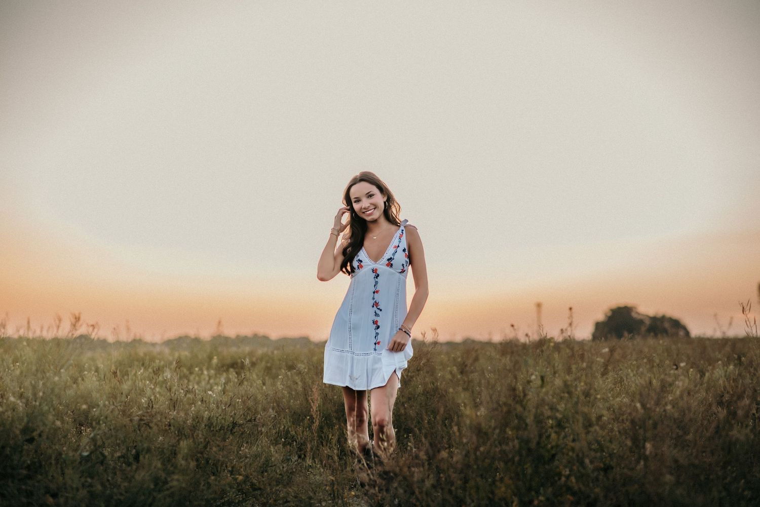 A breezy white dress catches the evening light in a rural wildflower field.