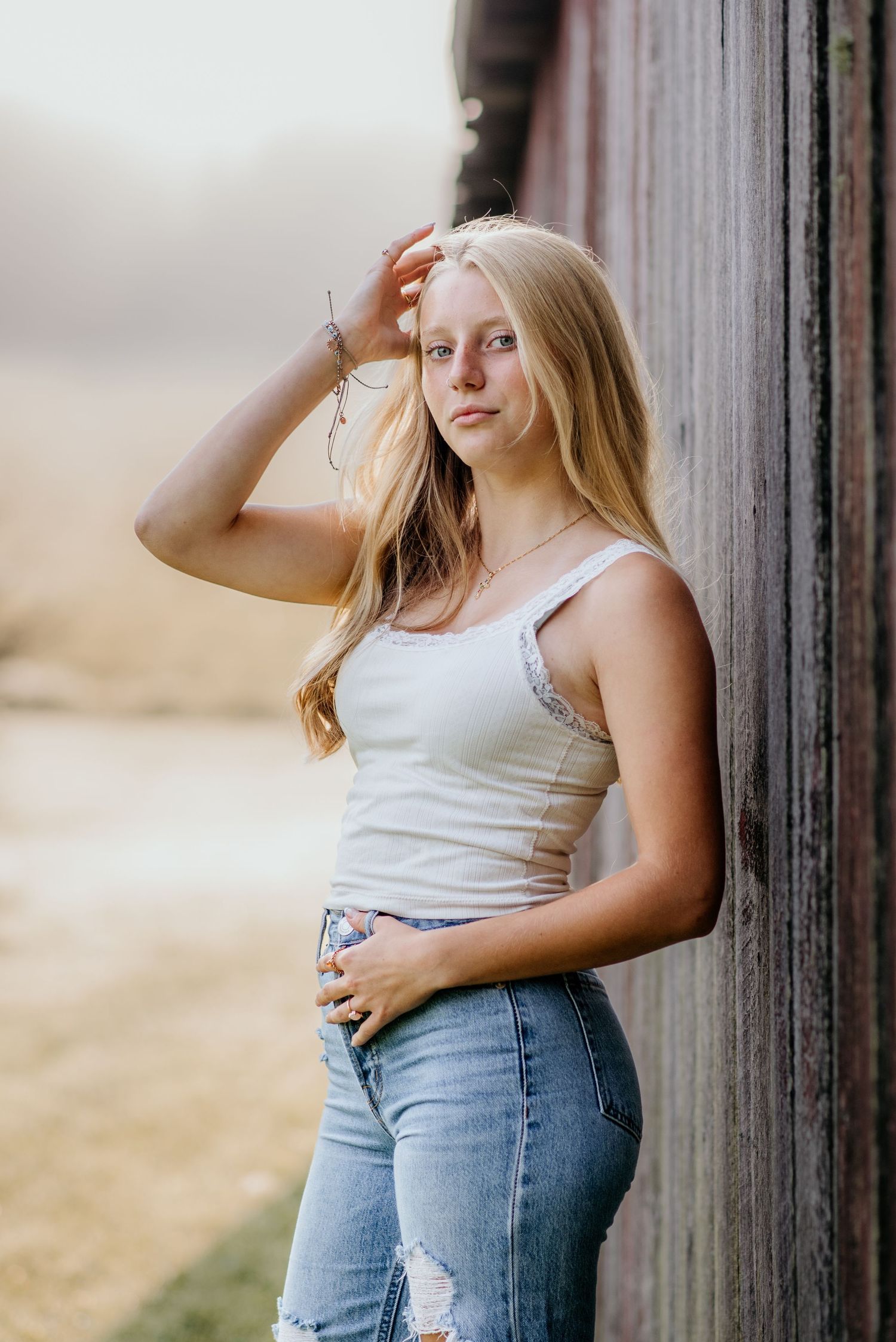 Natural light portrait against rustic barn wall in casual summer outfit.