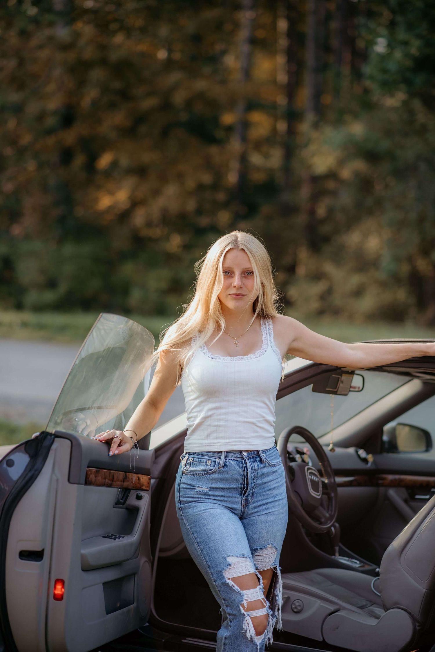 Casual photoshoot with convertible car featuring distressed denim and white tank top styling.