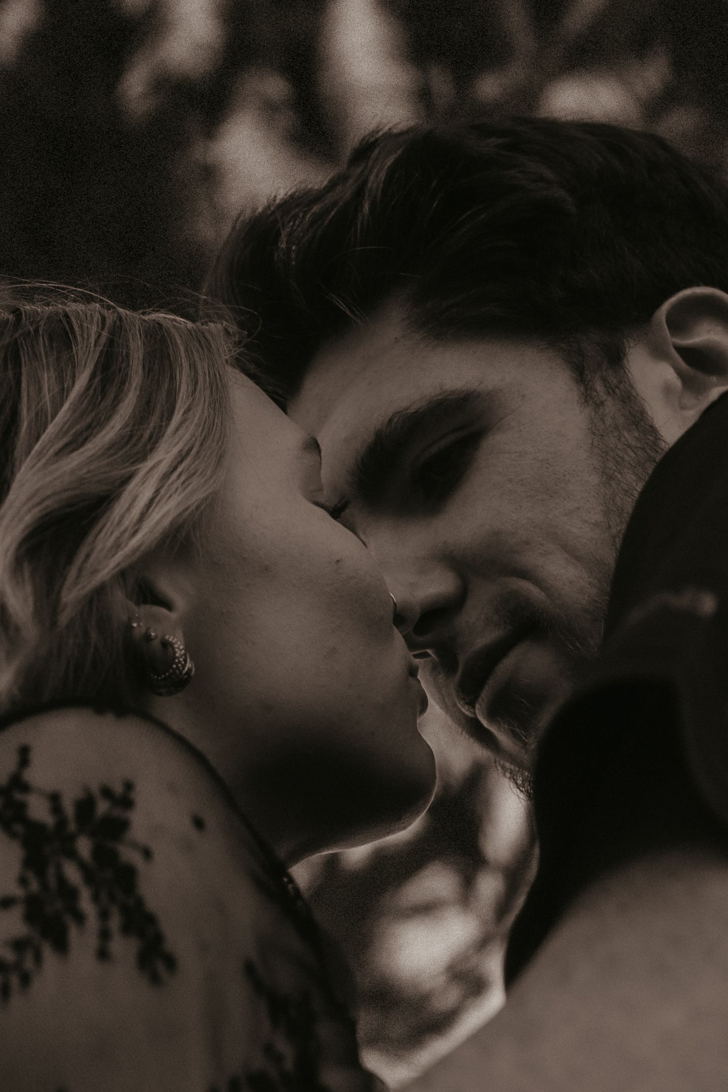 A romantic black and white close-up photo of a couple sharing an intimate kiss in moody lighting.