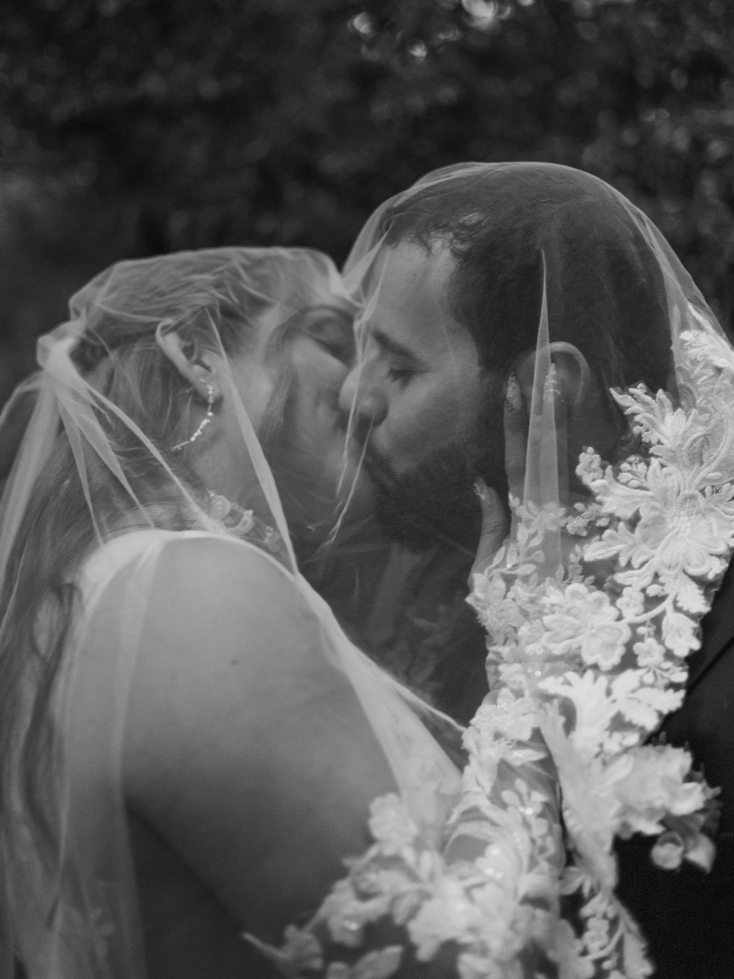 Photo by Bendito Recuerdo in Costa Rica, newly wedded couple kissing under the bride's veil may be in black and white