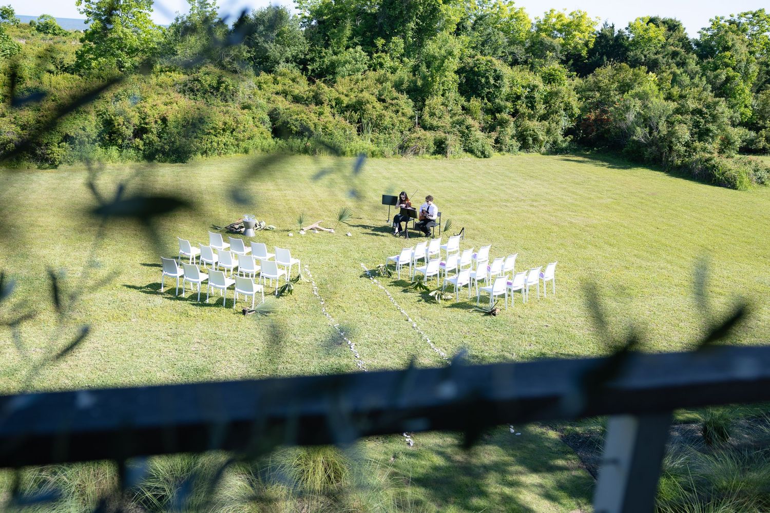 Outdoor wedding ceremony setup with white chairs arranged on green lawn.