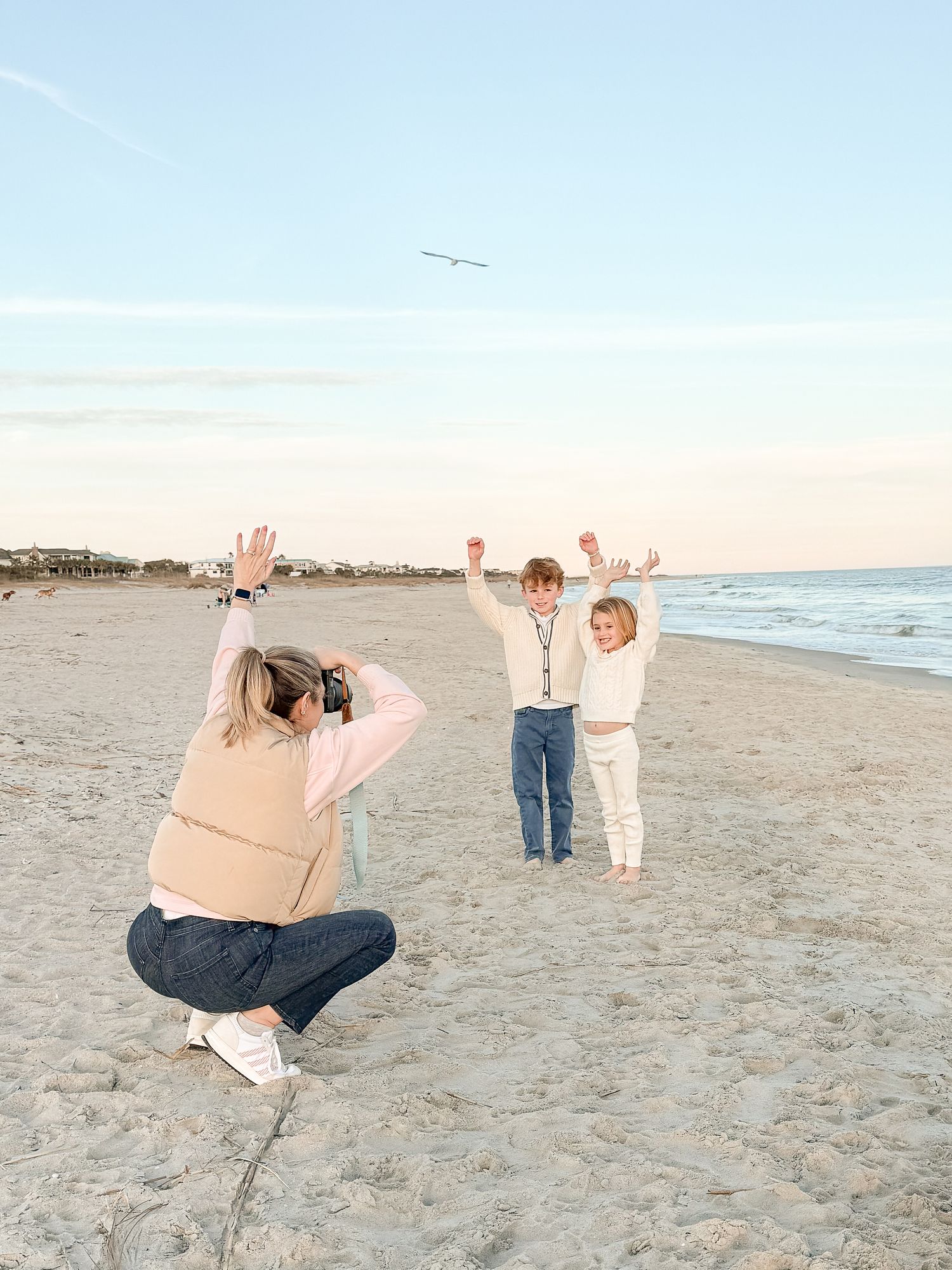Four connected images show a photographer in action capturing moments of people walking along a sandy beach at sunset.