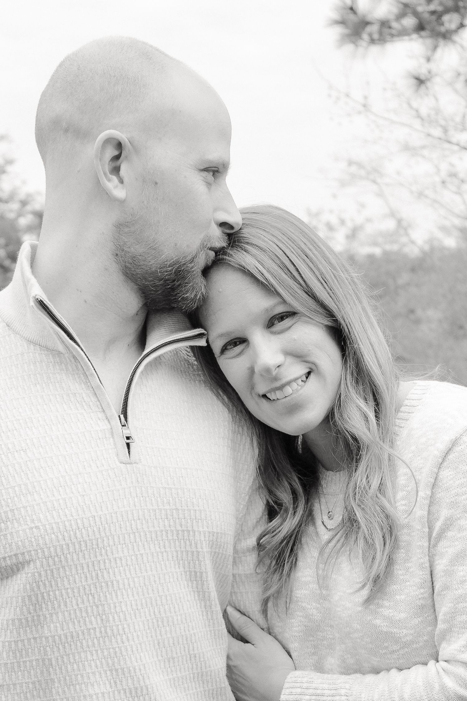 A romantic black and white photo series showing tender moments between a couple in casual attire outdoors.