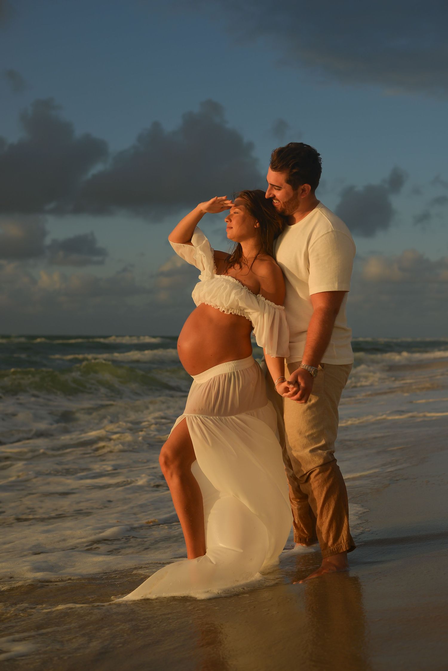 mother to be looking at the sunrise with daddy holding hands