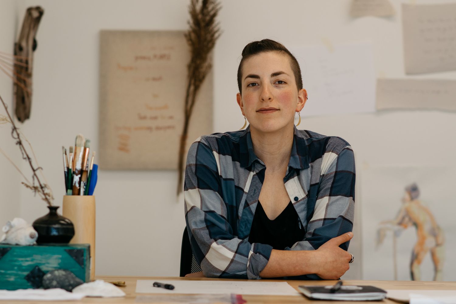 Artist working at desk with sketches and art supplies in creative workspace.