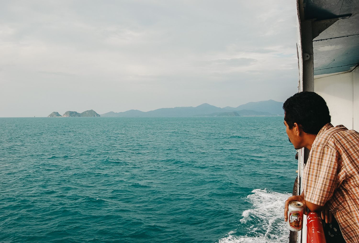View of distant islands from a boat on turquoise ocean waters.