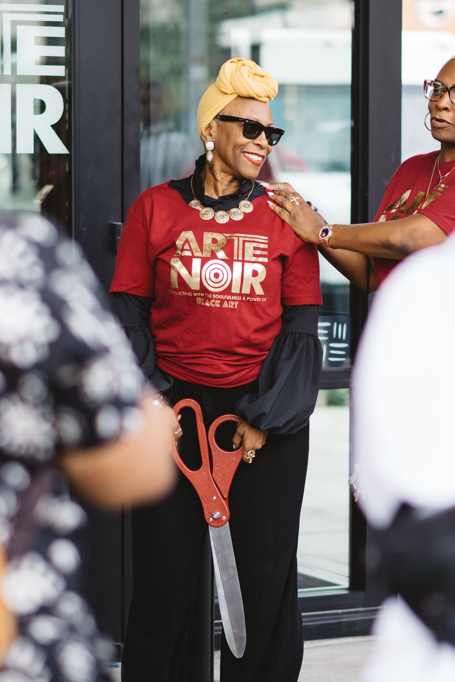 Person in red NOIR shirt posing confidently outside a retail store.