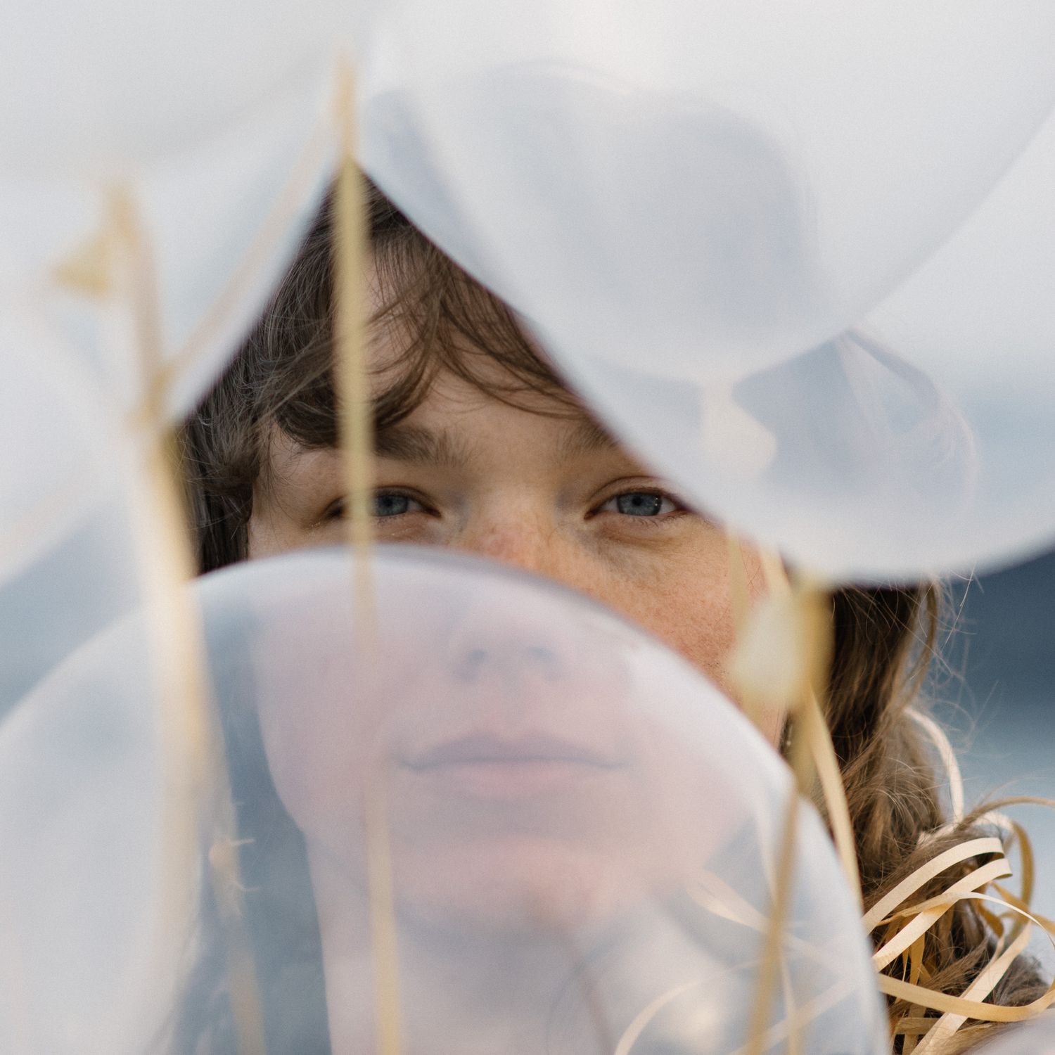 Ethereal close-up shot through white translucent balloons creating a dreamy effect.