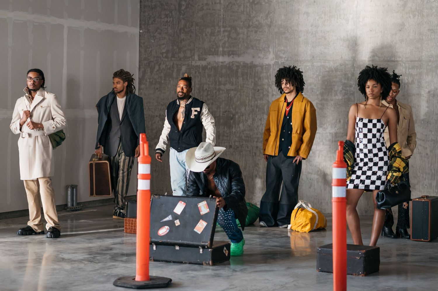 People in casual attire standing along concrete wall with traffic barriers.