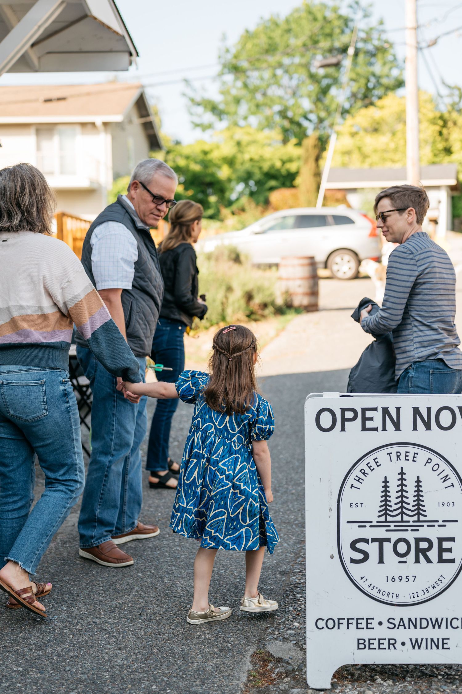 People walking near a storefront with coffee and sandwich signage.