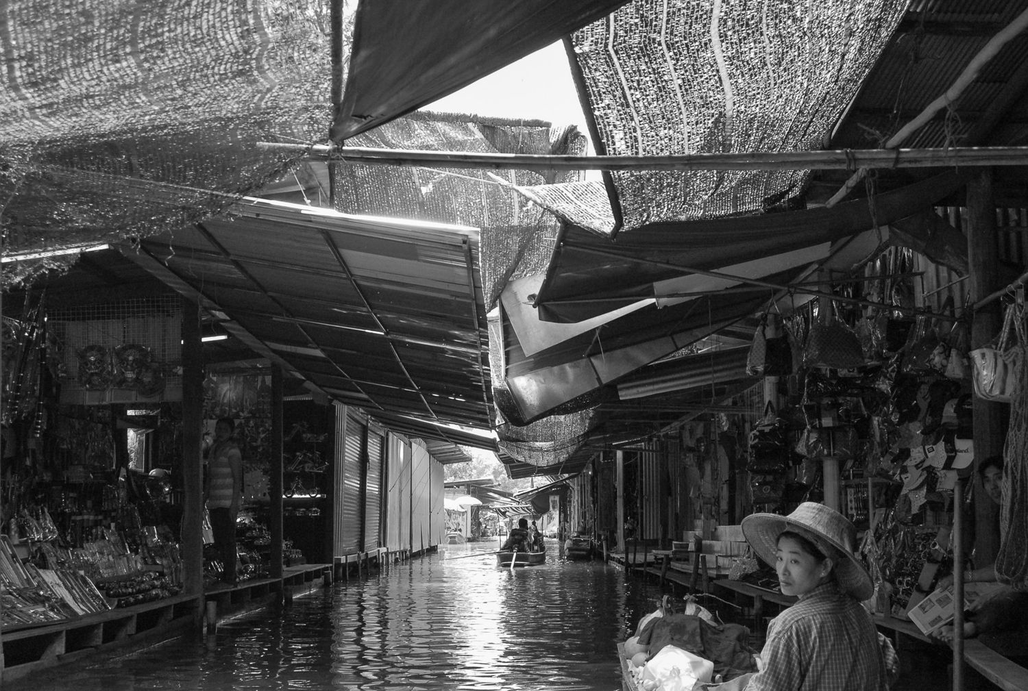 Covered market alley with hanging tarps creating shade in black and white.