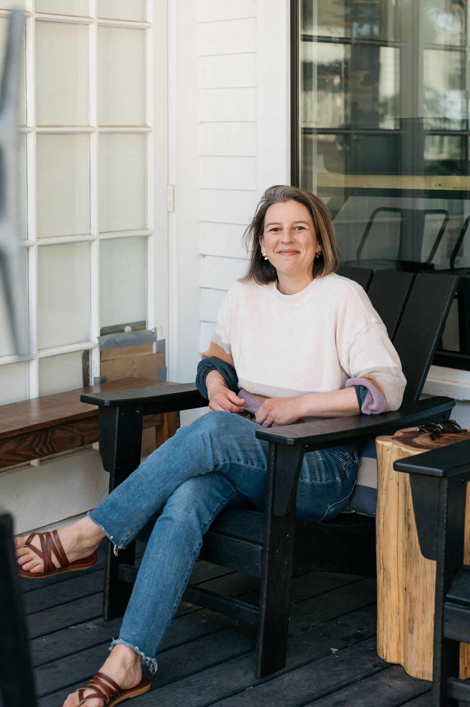 A person relaxes on a black outdoor bench with wooden accents.