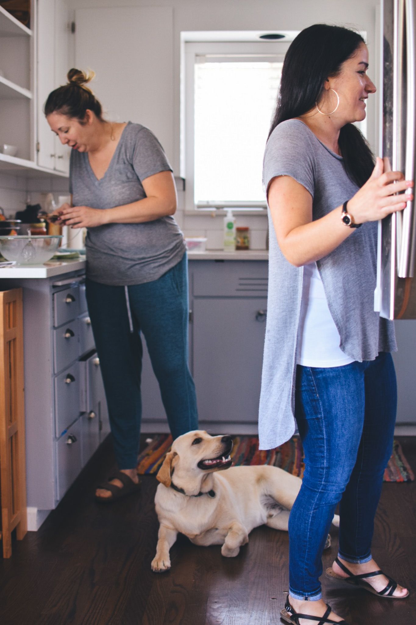 Yellow Labrador dog playing with people in a modern kitchen with hardwood floors.
