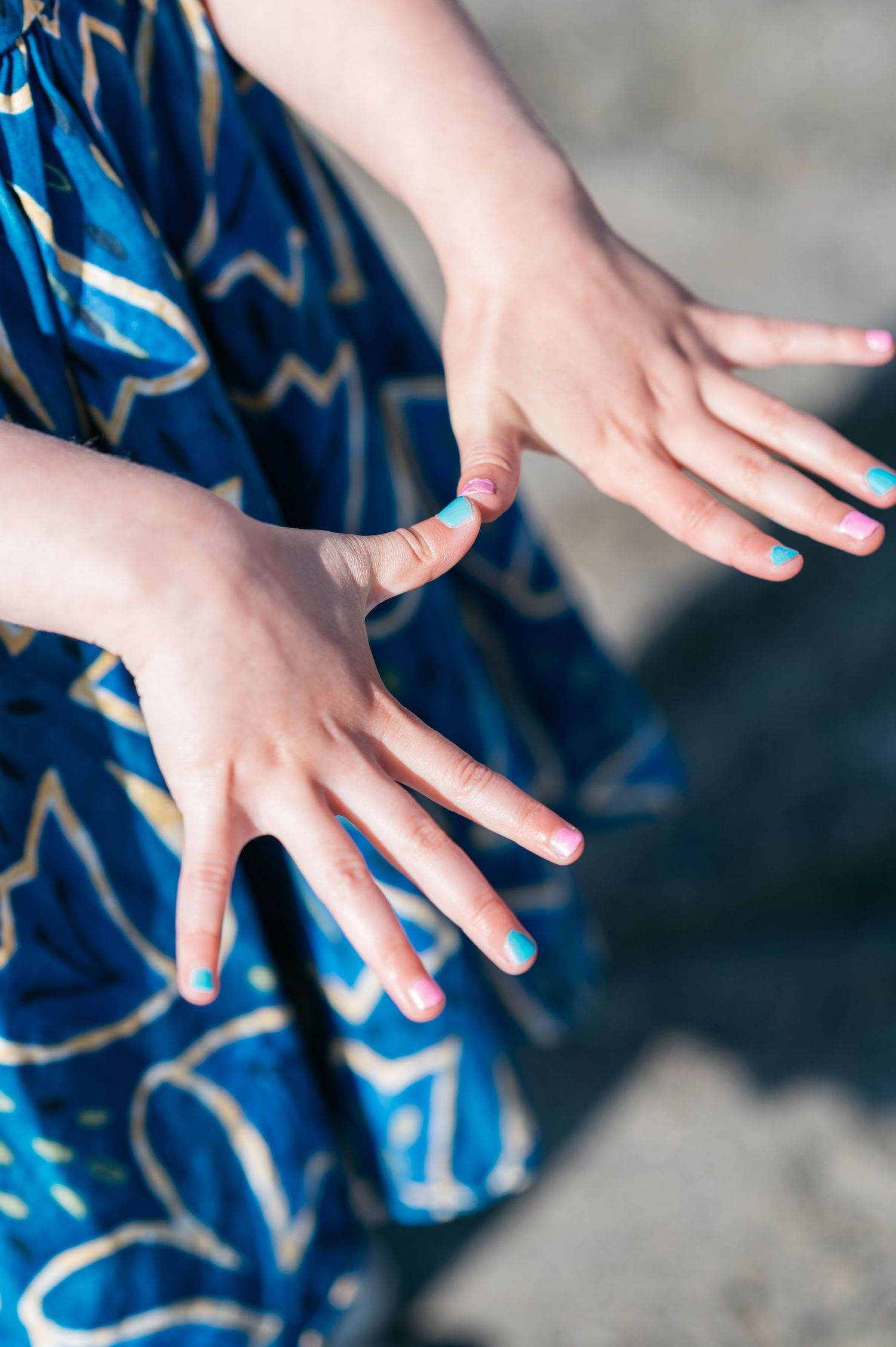 Close-up of small hands against a blue patterned dress.