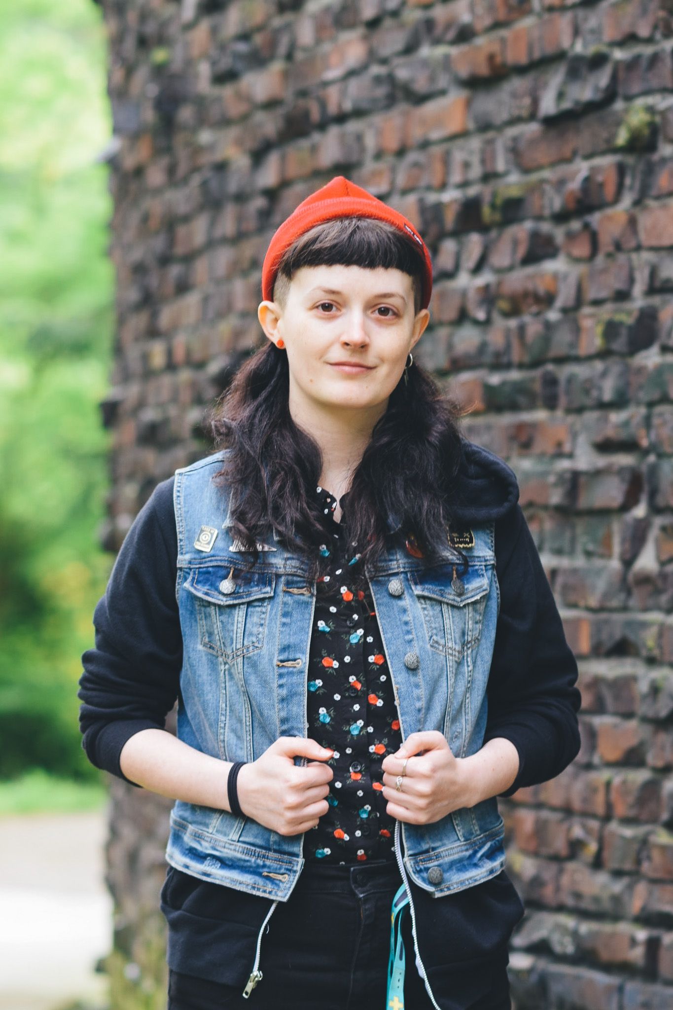 Street style portraits with denim jacket and red beanie against brick wall backdrop.
