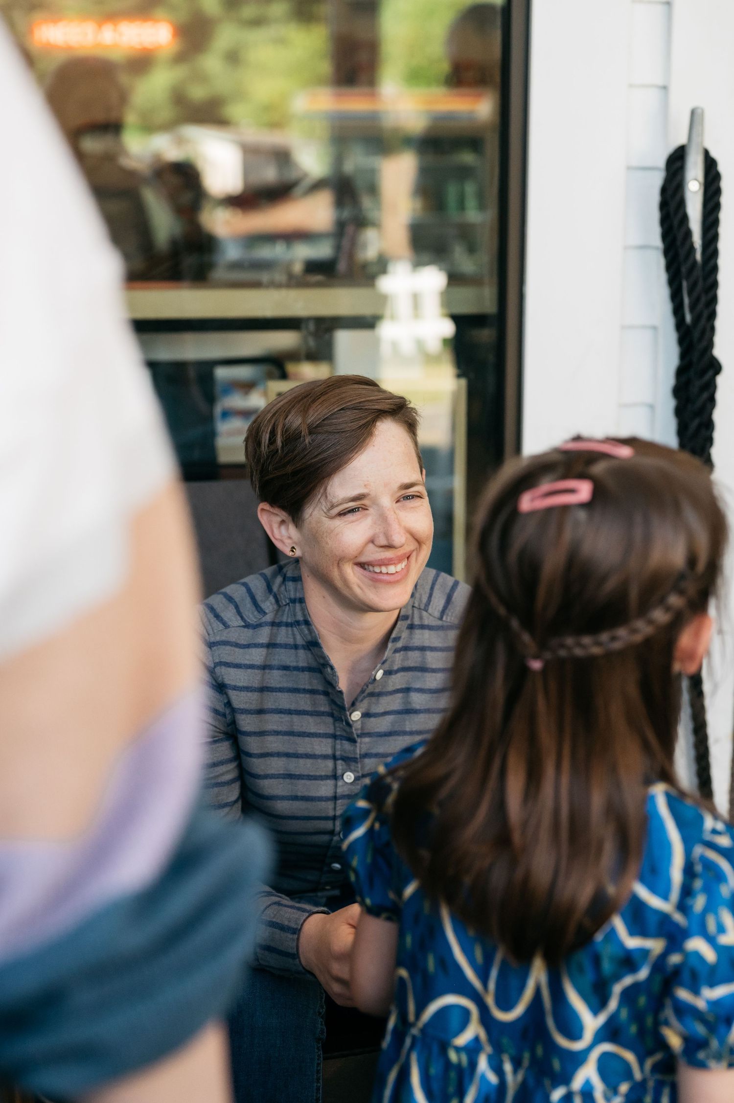 People interacting and smiling in a casual outdoor restaurant setting.