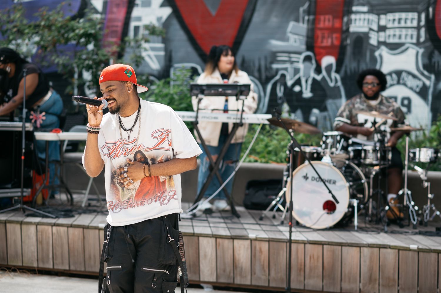 Musicians performing on an outdoor stage with instruments and equipment.