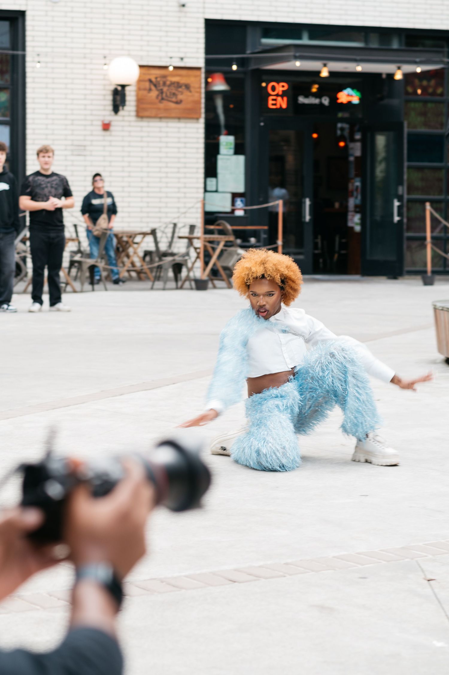 A person in a light blue outfit performing a breakdance move on a concrete surface.