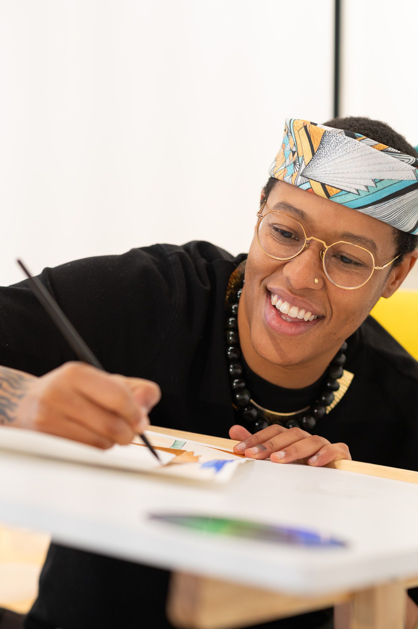 Student smiling while working on creative project at desk.