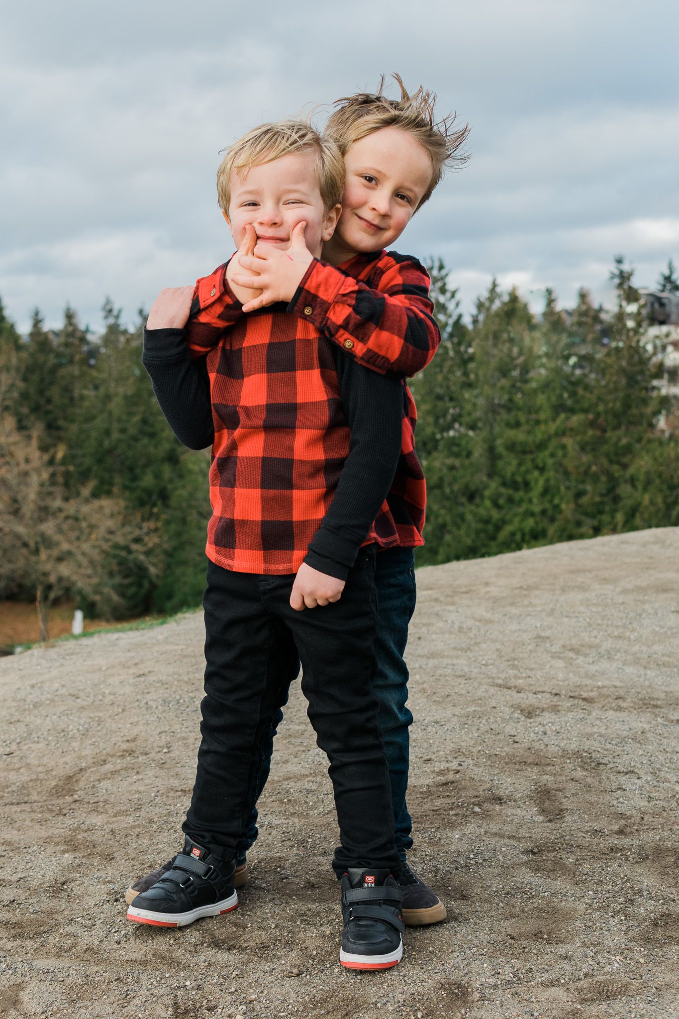 Playful outdoor photos in buffalo plaid and black clothing on rocky terrain.