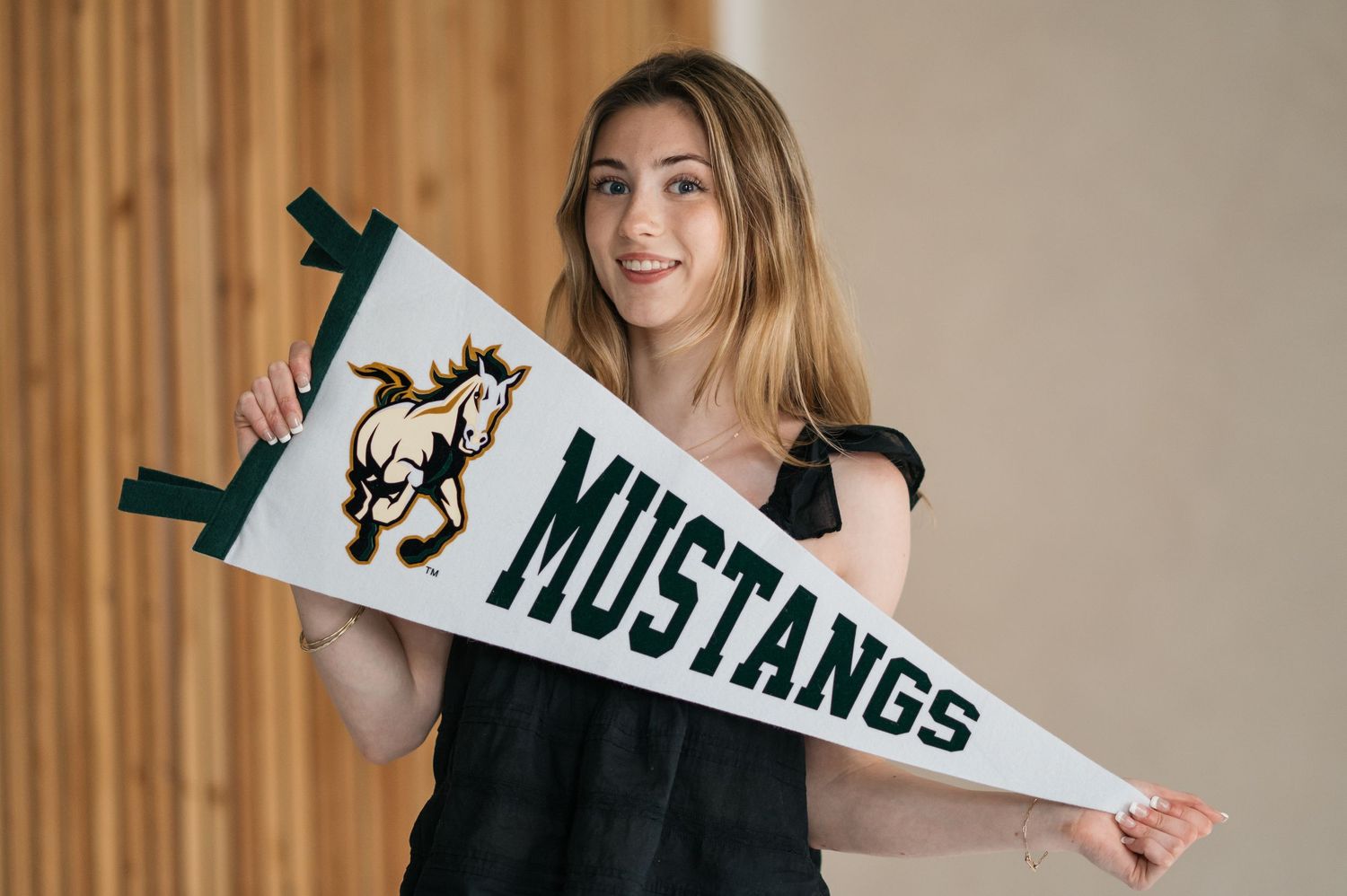Someone holding and displaying white Mustangs pennants against a neutral background.