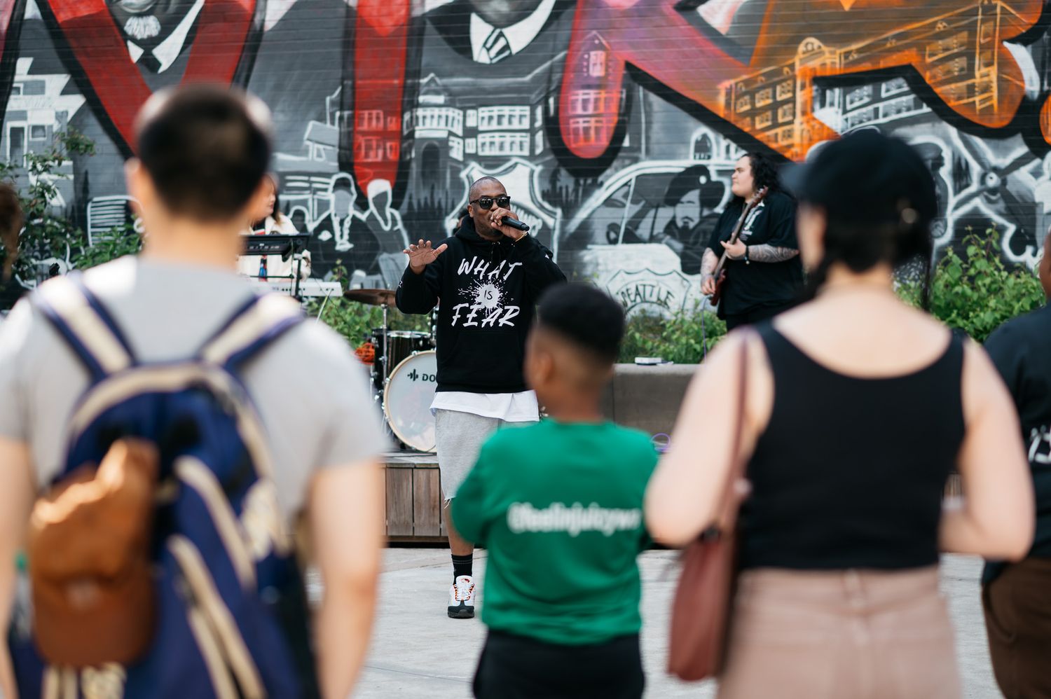 People walking past colorful street art and murals in an urban setting.