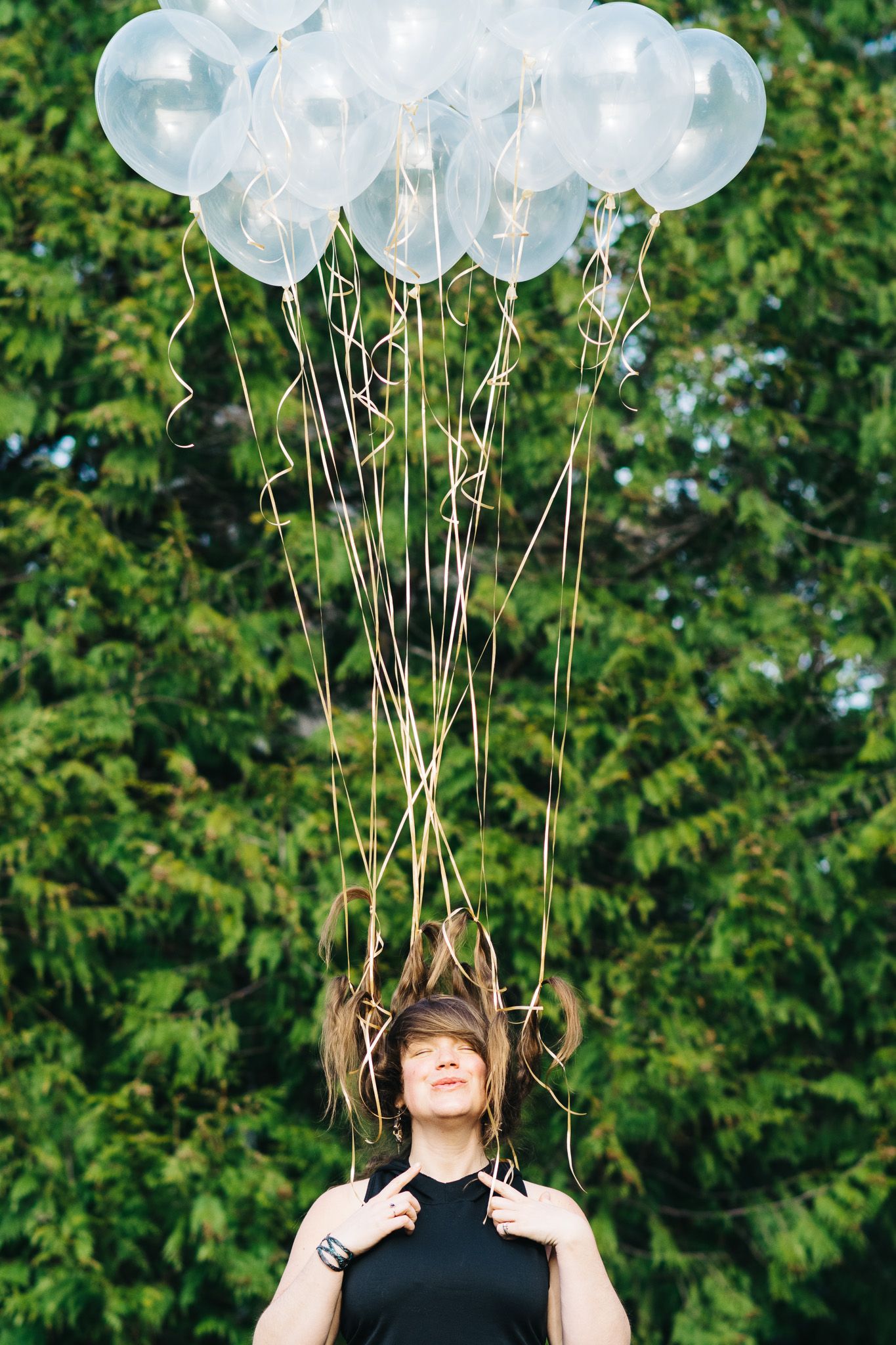 White balloons floating against green foliage in an outdoor setting.