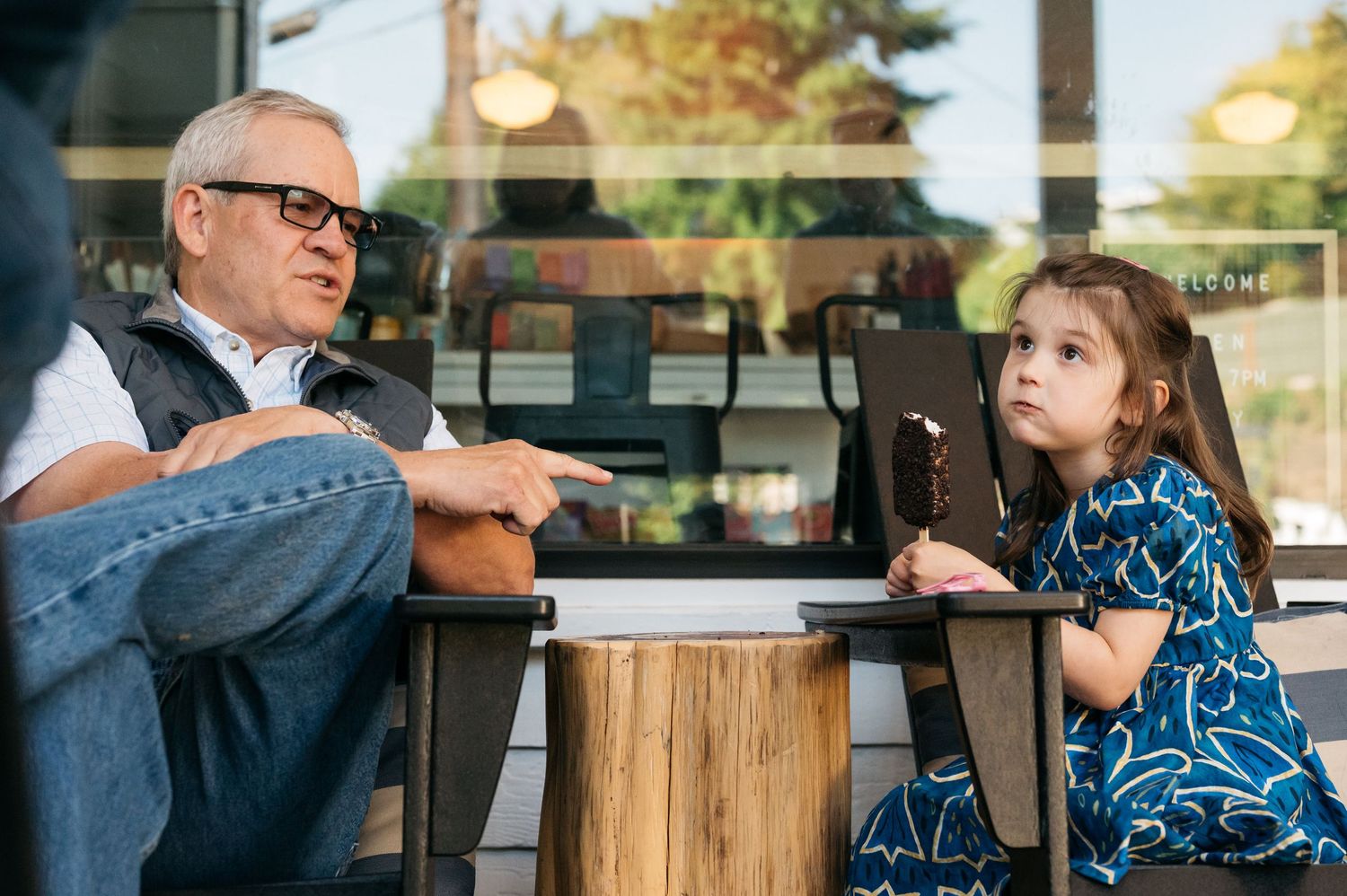 People gather around a wooden stump table at a coffee shop.