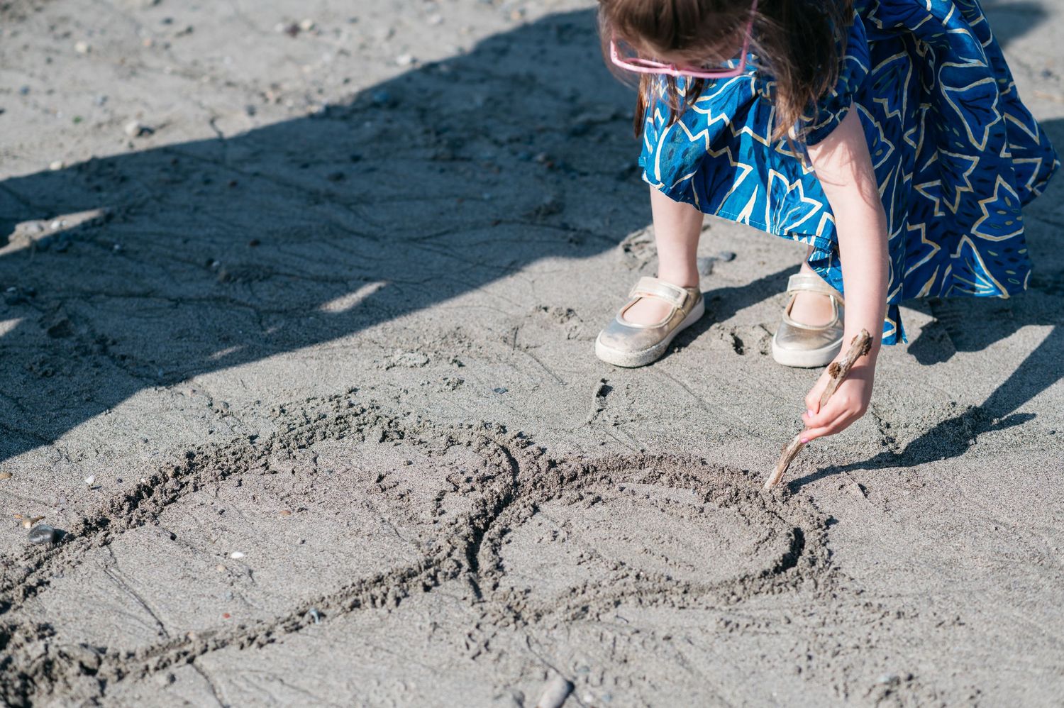 Someone drawing a heart shape in the sand on a beach.