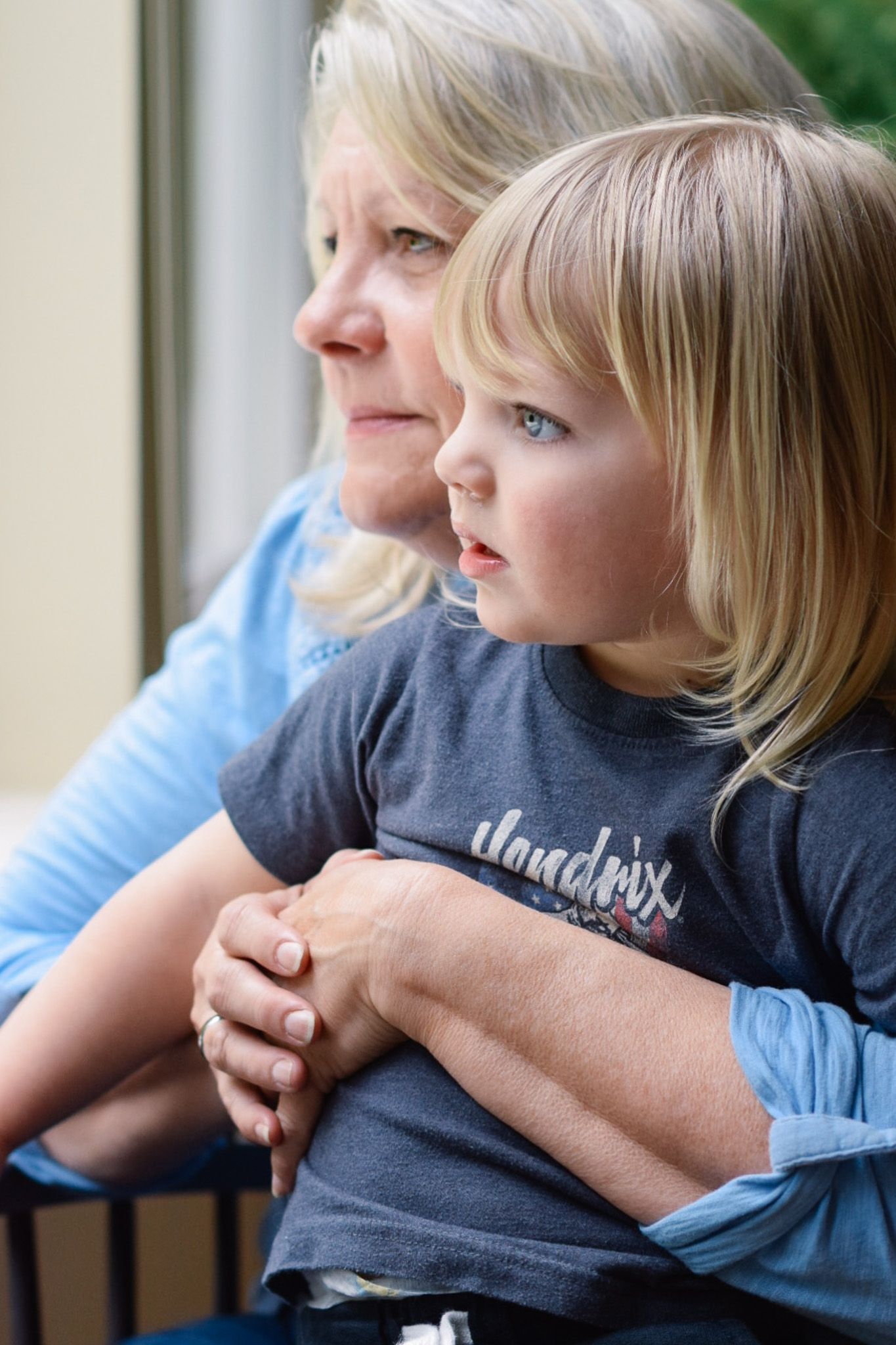 A tender moment between two generations as they gaze out a window together.