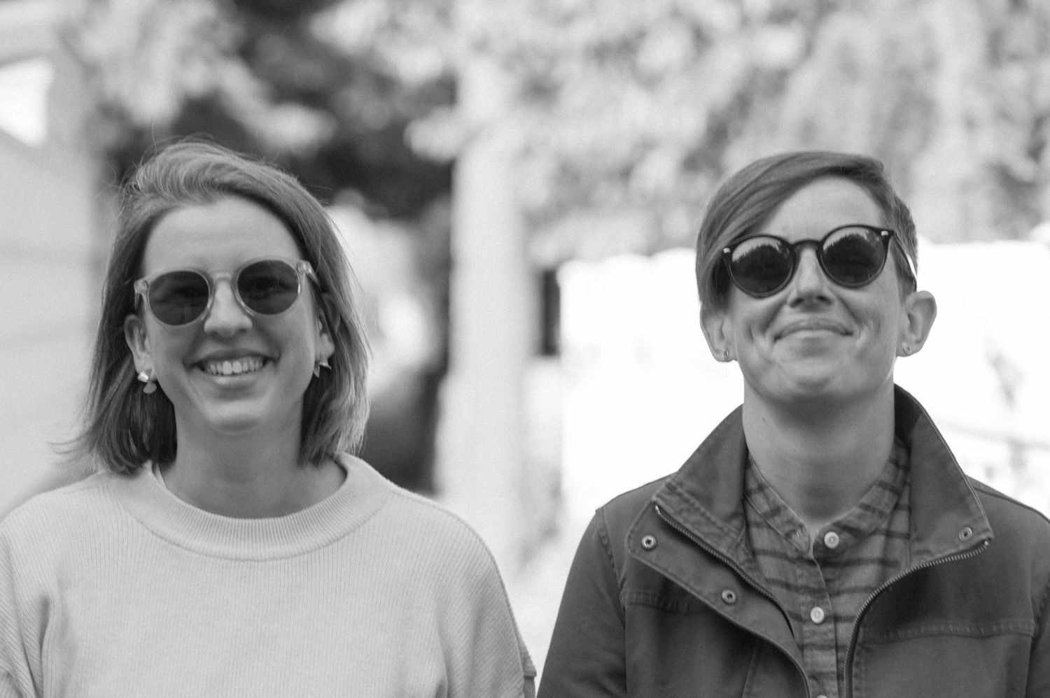 A group wearing sunglasses poses together outdoors on a sunny day.