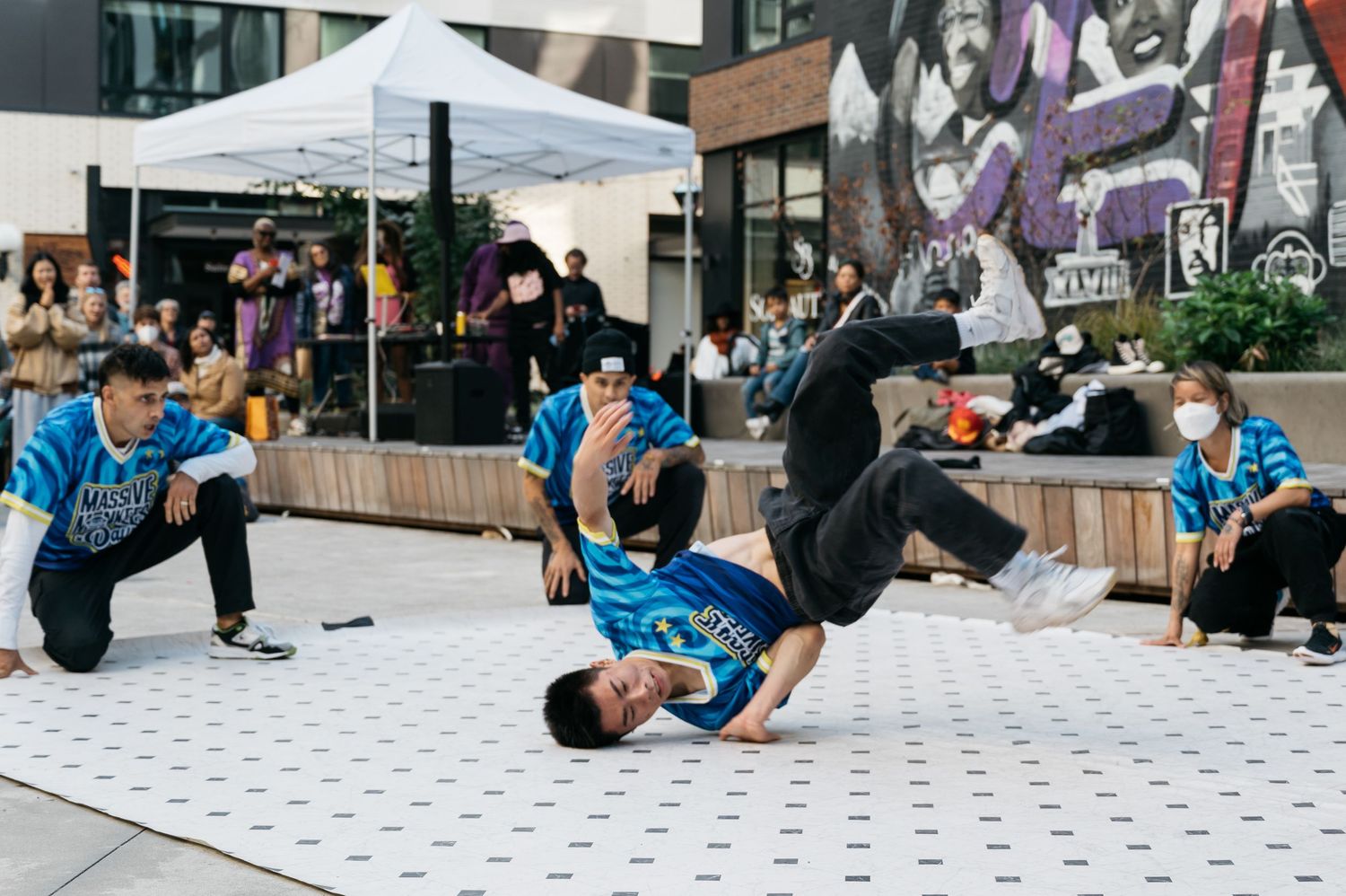 Breakdancers performing acrobatic moves on a tiled floor during a street performance.
