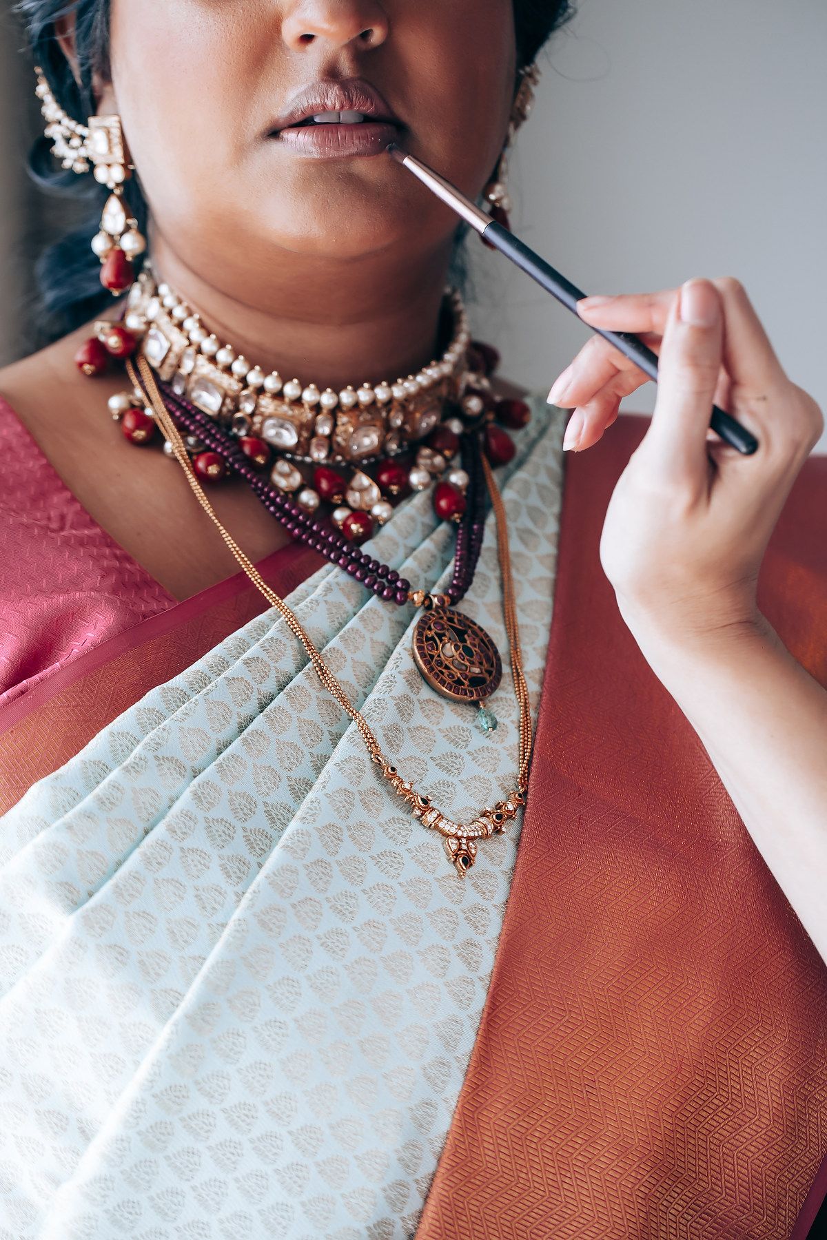 Close-up of traditional South Asian jewelry and makeup application.