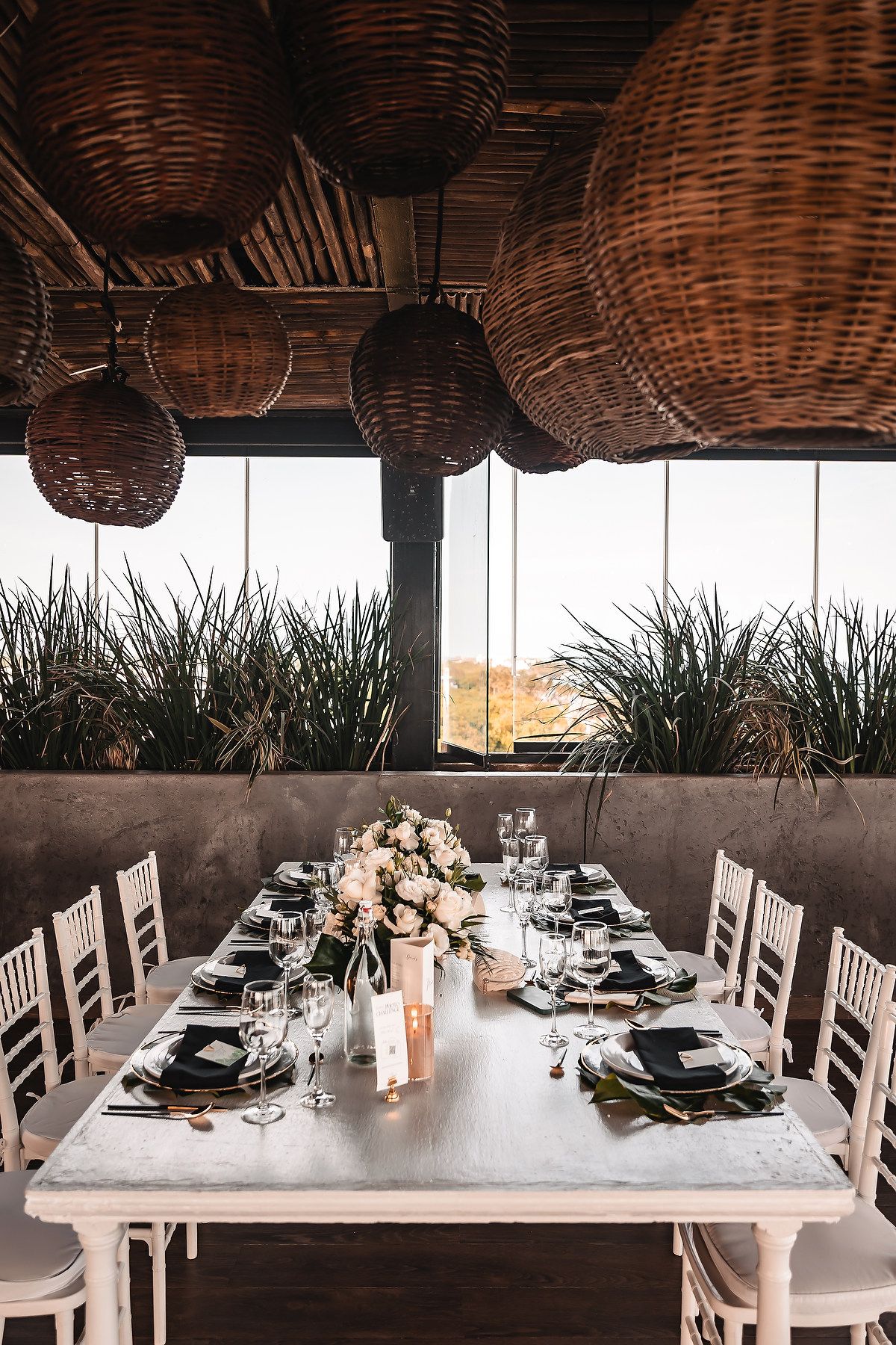 Elegant wedding reception table setup with woven basket lighting and coastal decor.