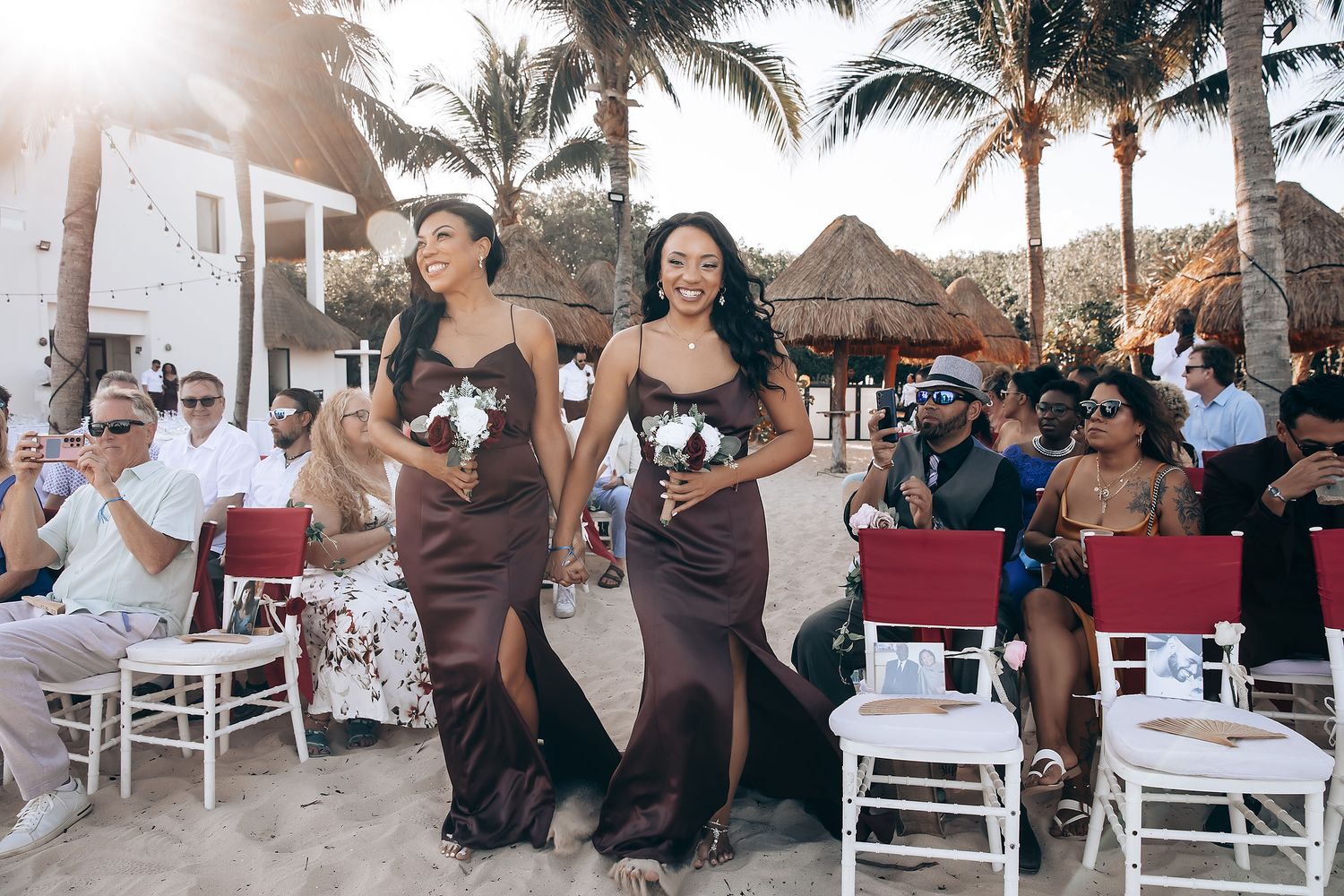Wedding celebration at a tropical beach venue with palm trees and white decor during sunset.