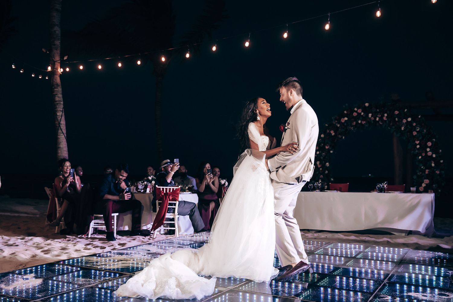 Wedding reception setup with string lights and elegant table settings at night.