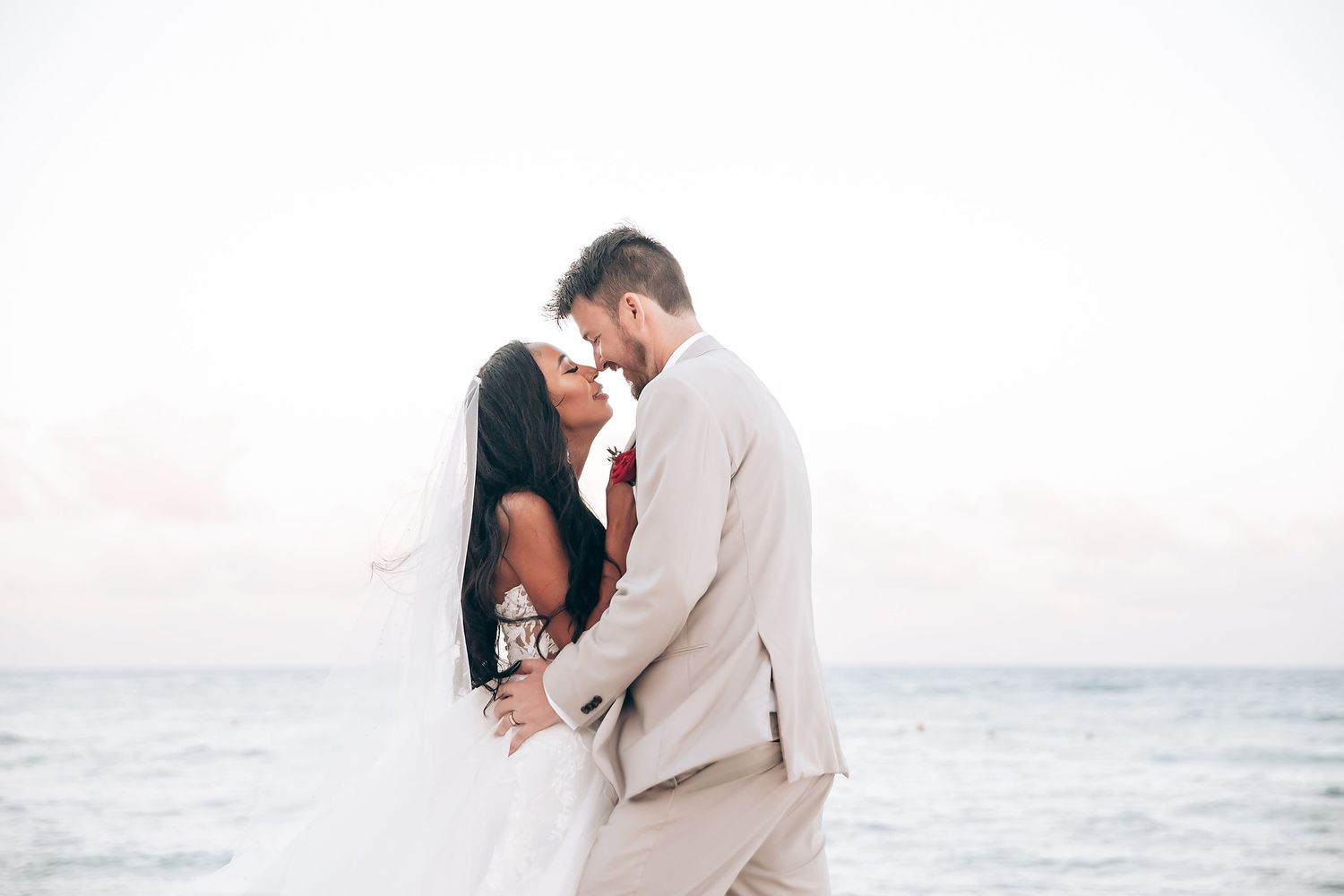 Intimate beach wedding photos showing couple in romantic poses against ocean backdrop.