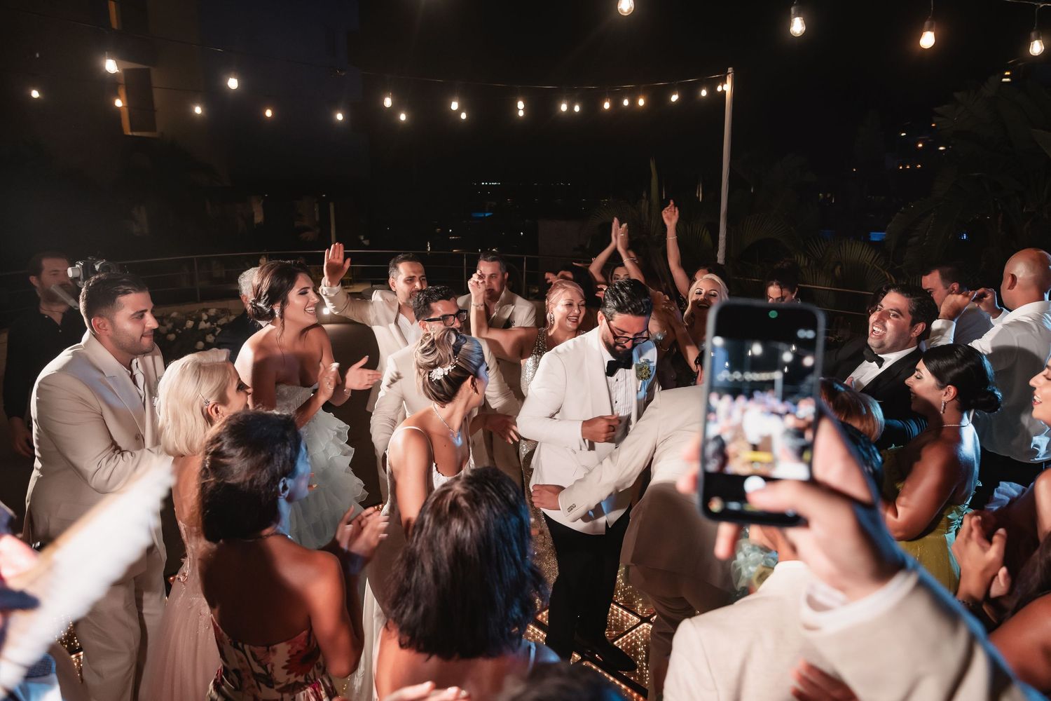 Wedding guests form an energetic dance circle during the reception celebration.