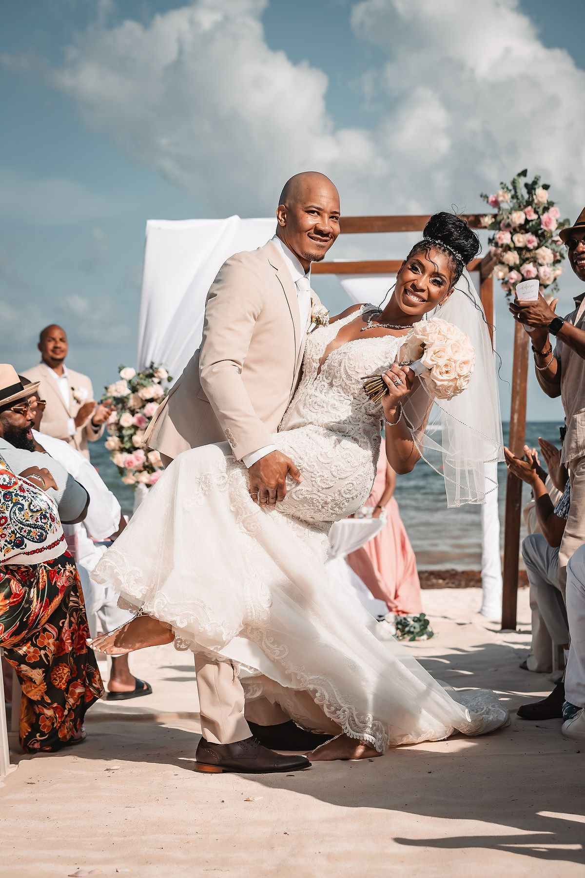 Joyful wedding celebration moment on a sunny beach with guests cheering.