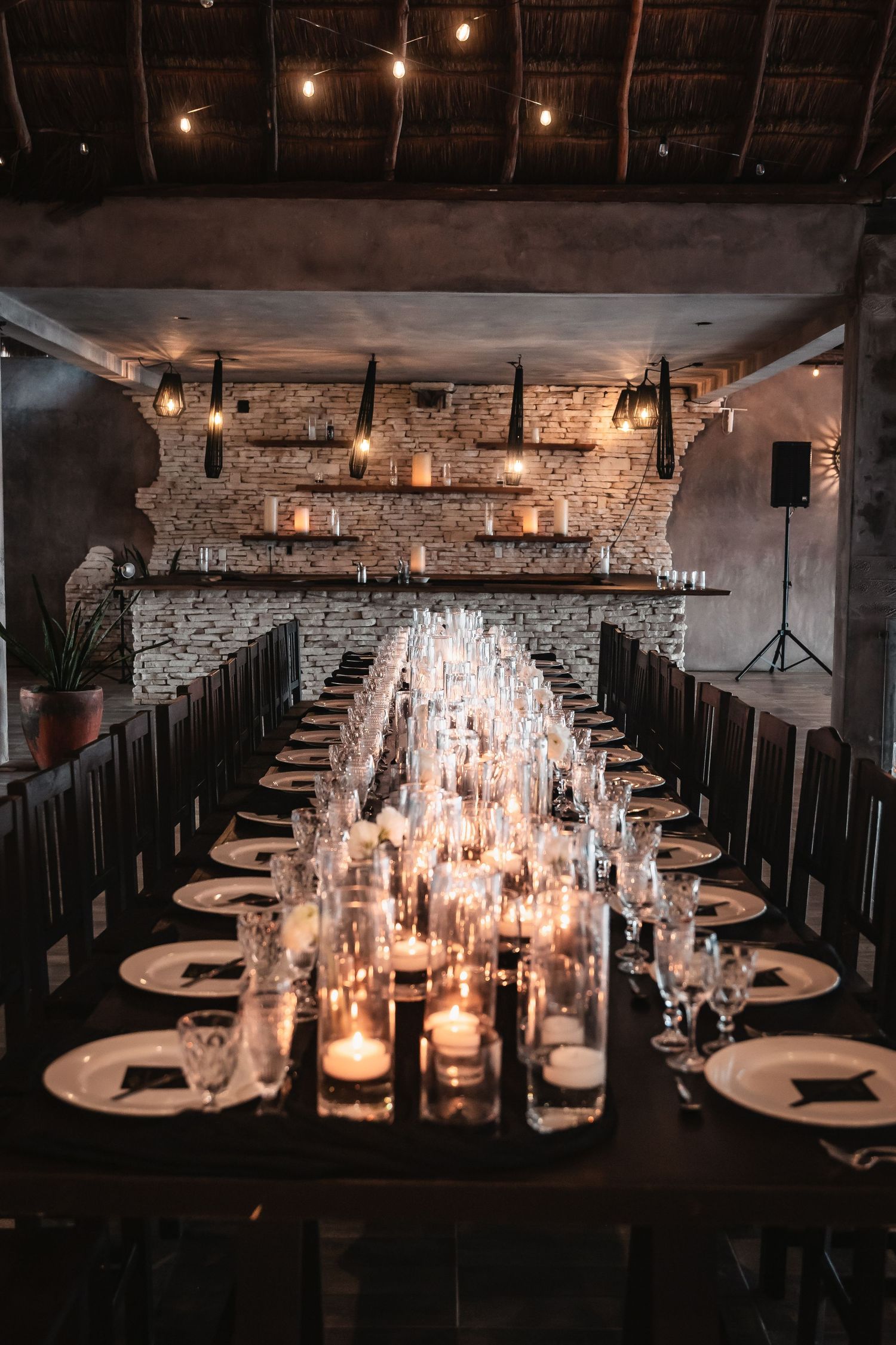 Candlelit wedding reception tables with glass centerpieces and elegant place settings.