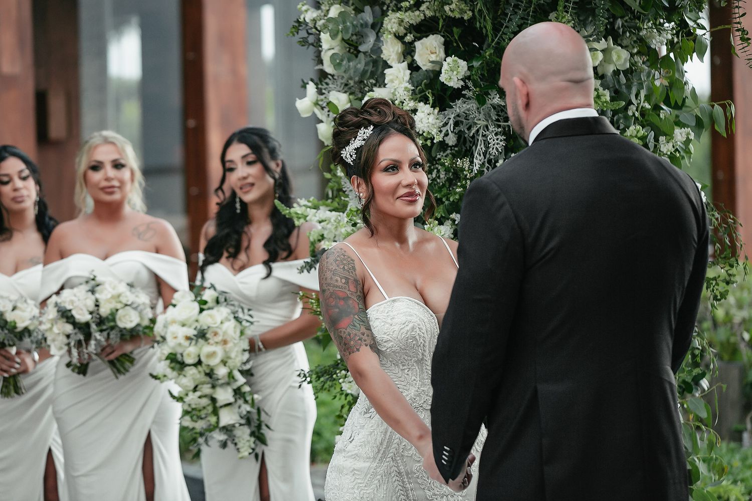 Wedding party members pose together near elegant floral arrangements.