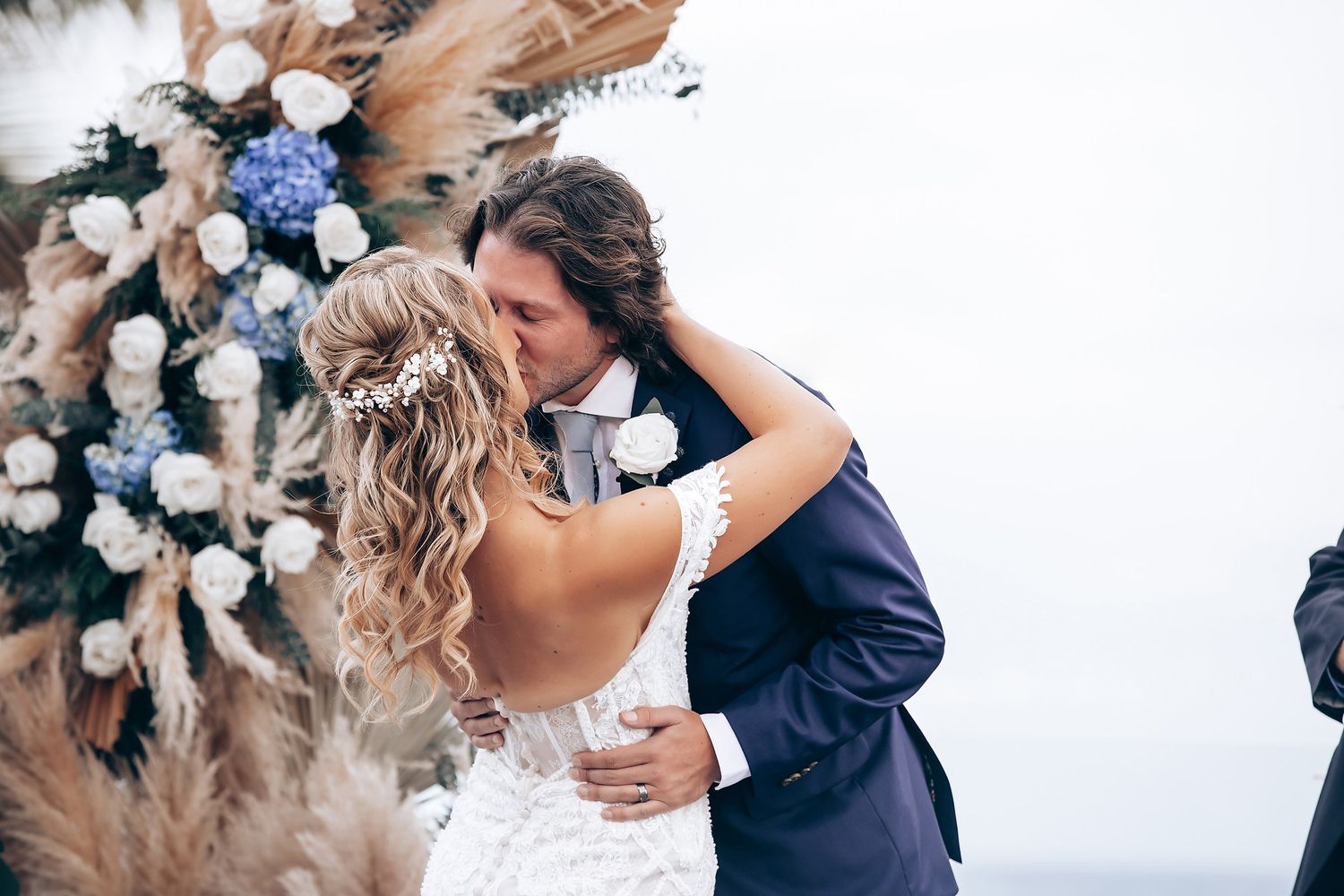 Romantic wedding moment captured with blue hydrangeas and white floral arrangements.