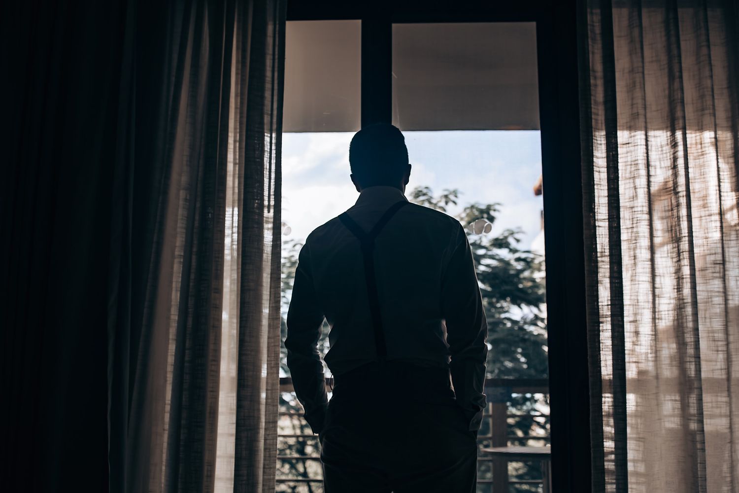 Silhouetted figures against window with curtains creating dramatic lighting effect.