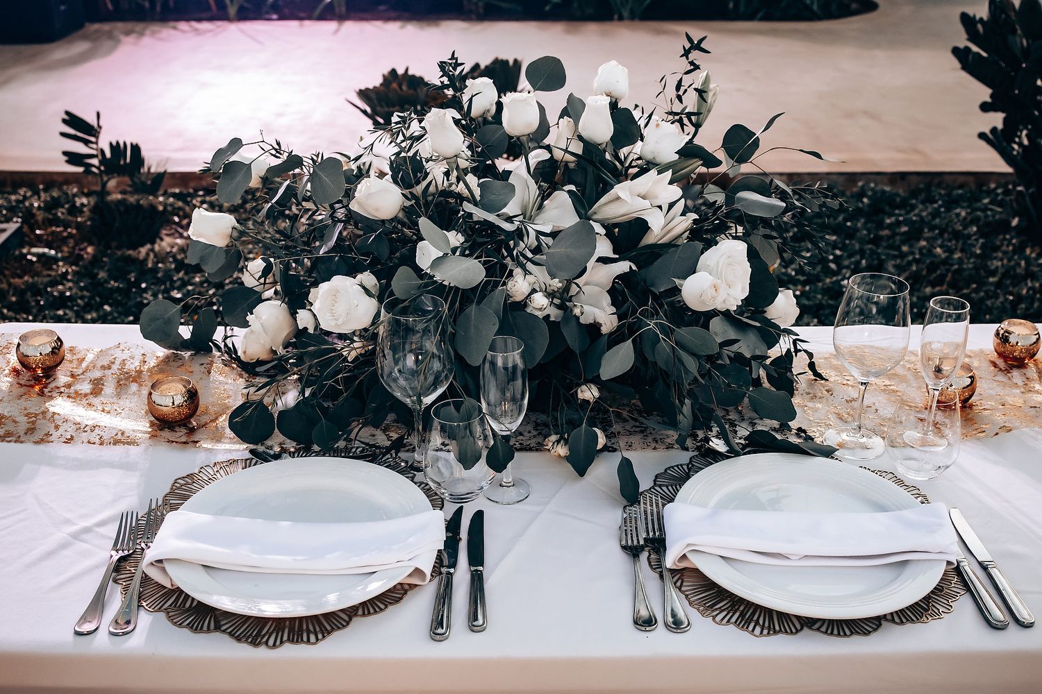 Elegant wedding table setting with white floral centerpieces and crystal glassware.